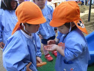 ダンゴムシを見せ合う3歳児