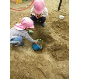 穴に土を入れる2歳児