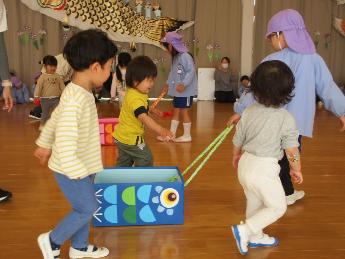 2歳児の追いかけ玉入れ。かごは5歳児が曳く、段ボールで作ったのこいのぼり車