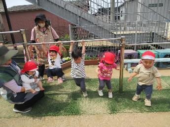 鉄棒にぶら下がる0歳児、1歳児