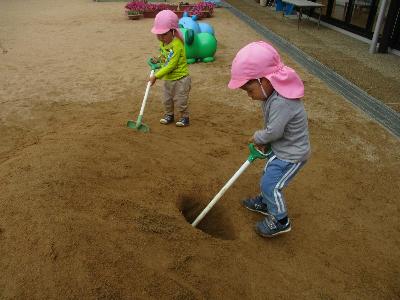 5歳の真似をして5歳の堀った穴にスコップをいれてドリルのようにする2歳児