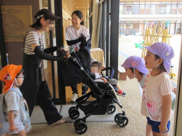 挨拶運動をする5歳児と返事を交わす3歳児親子