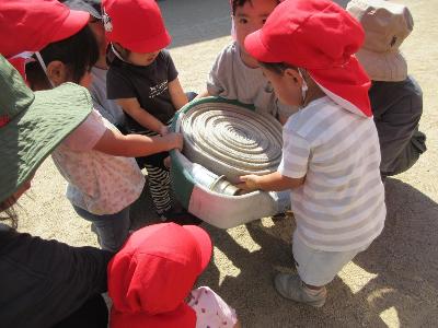 消防車のホースを持たせてもらう1歳児