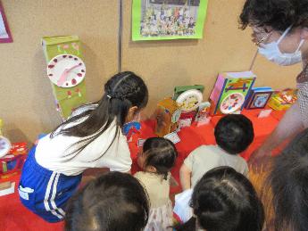 0・1歳児が年長児のクラスの時計を見に来ている場面