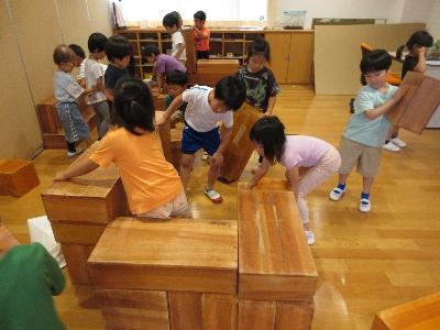大型積み木で飾る台を作る5歳児