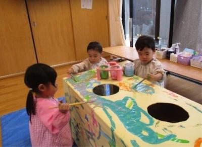 障害物コースのトンネルに色付けをする1歳児