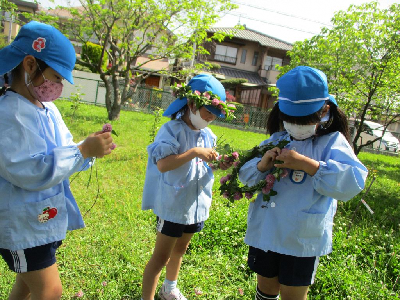 シロツメクサで花冠を作る幼児