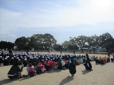 小学生と一緒に校長先生の話を聞く園児