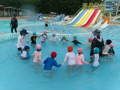 プールで輪になって遊ぶ年長児