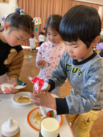 ホットケーキにトッピングをする園児