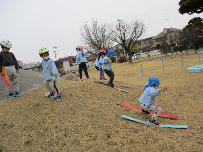 築山でスキージャンプごっこをする園児