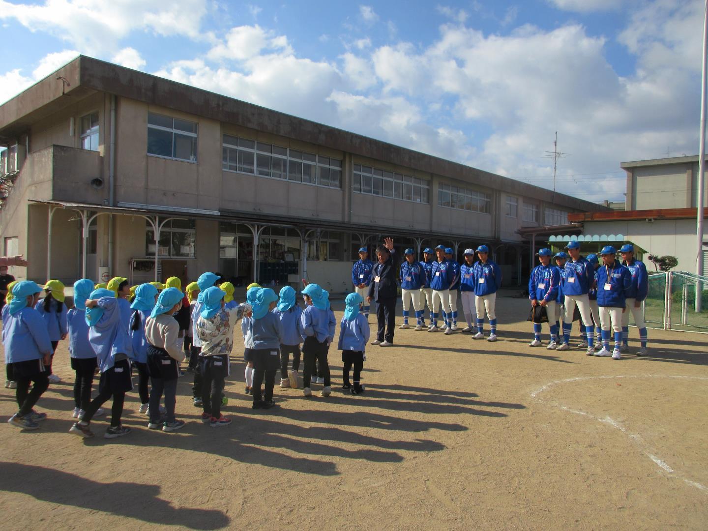 園庭で高校野球部と挨拶をする子ども達