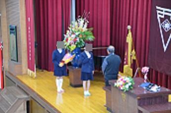 記念講演をしていただいた講師に、児童が感謝の言葉と花束を贈っている。