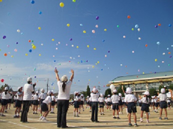 運動会の120周年記念セレモニーで、夢を託した風船をみんなで空に飛ばしている様子