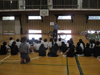 3年生が、警察の方による自転車の乗り方の説明を聞いている。