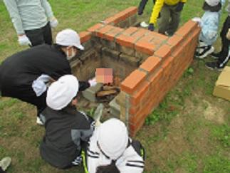 学校にあるかまどで、児童たちが火をつけ、ポップコーンを作っている。