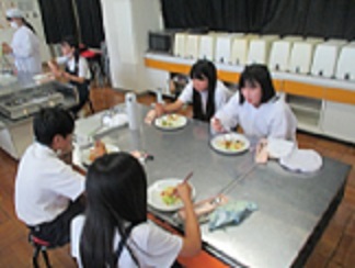 児童が自分たちで作った野菜炒めを食べている。
