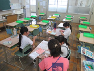 折り紙クラブで、児童たちが本を参考に紙を折っている様子。