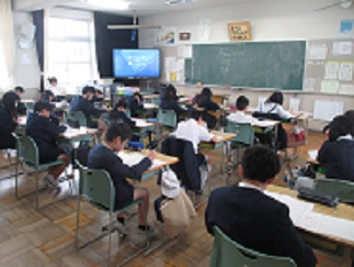 全国学力調査の様子。児童が問題用紙と解答用紙を受け取り、テストに臨もうとしている。