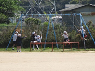 晴れの日の休み時間の様子。児童がブランコで遊んでいる。