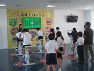 ごみ処理場で、自転車をこいで発電するゲームを通して、発電量について学んでいる。