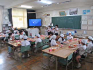 4年生と2年生の交流の様子。4年生児童が前でいただきますのあいさつをしている。