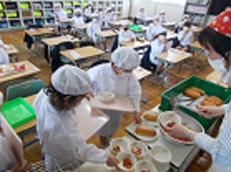 1年生がはじめて給食の準備をしている様子。お盆を持ち、お椀やお皿を乗せていっている。