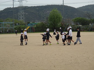 1年生を迎える会の後、6年生と1年生が一緒に運動場で遊んでいる。