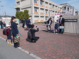 校門前で、入学する1年生と保護者が記念撮影をしている。