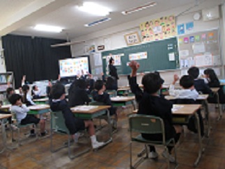 1年生の参観授業。児童が元気に挙手している。