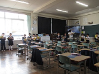 2年生の参観授業。児童が円形に並んで教科書を音読している。