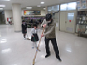 校長室の前を、児童が校長先生と一緒にほうきで掃いている様子。