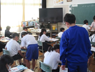 算数の授業で、中学生が児童の傍に立って教えている様子。