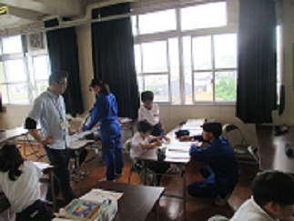 外国語の授業で、中学生が児童の様子を見たり、指導したりしている。