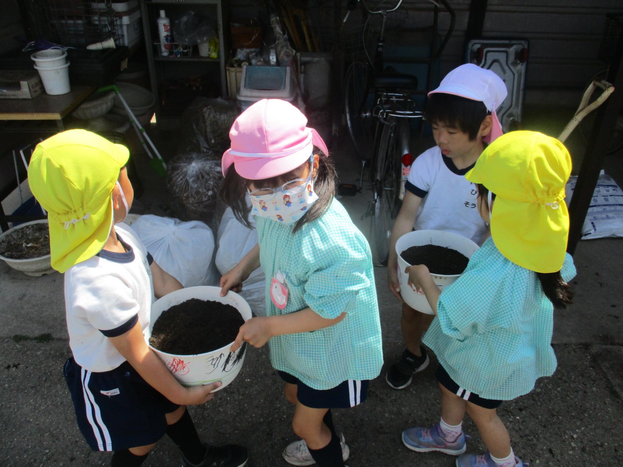 5歳児が4歳児の植木鉢を運ぶ手伝いをしている