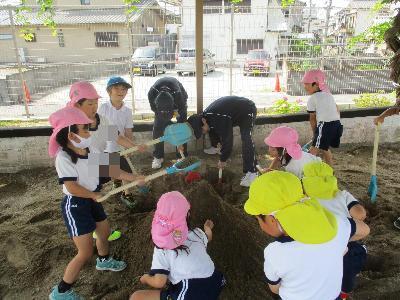 砂場遊びをする幼児と中学生