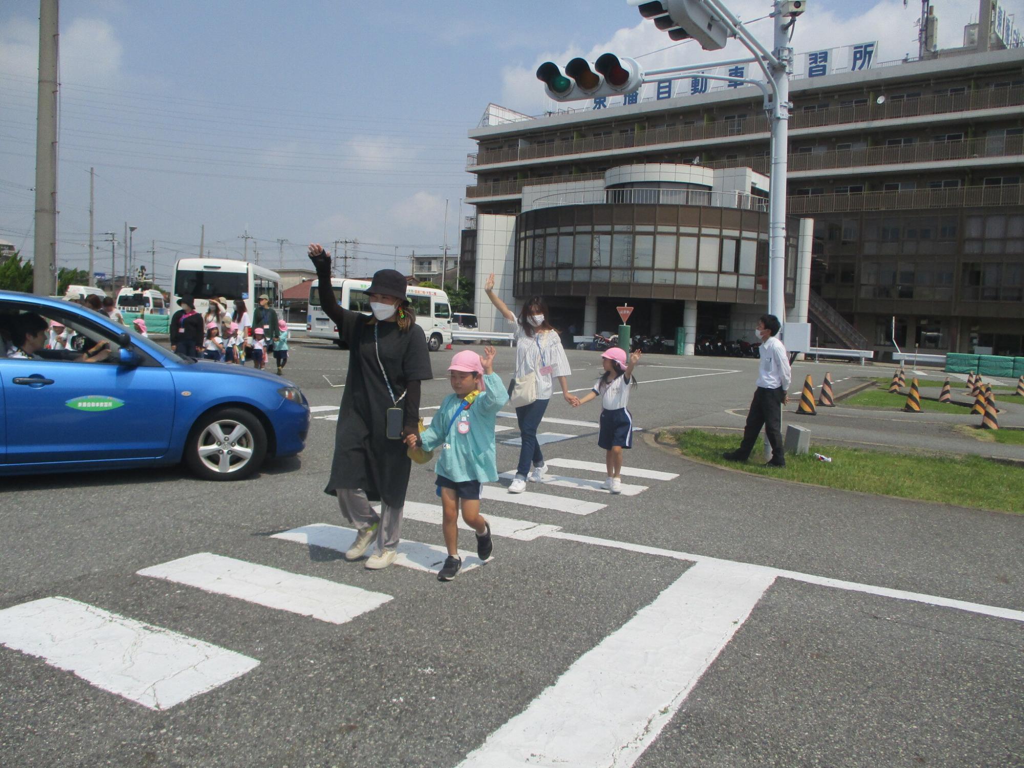 親子で手を上げて横断歩道を渡っている