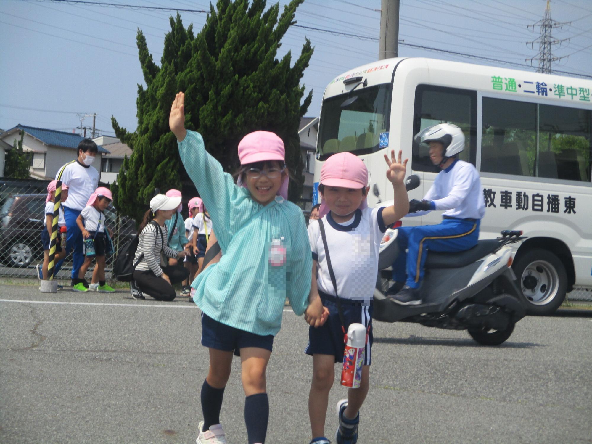 5歳児が2人で手を上げて道路を渡っている