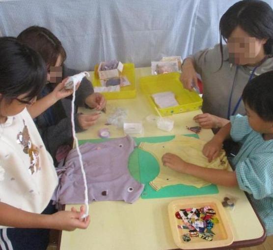 幼児が保護者とビーズや布でバッグを作っている