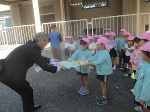 幼児が小学校の校長先生に招待状を渡している
