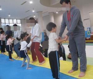 幼児が保護者と一緒にトランポリンをしている