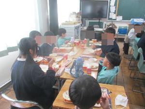 幼児が小学生と会話しながら給食を食べている
