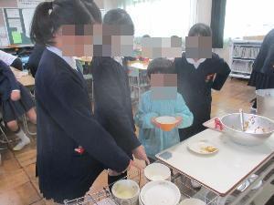 幼児が小学生に食器の片付け方を教わっている