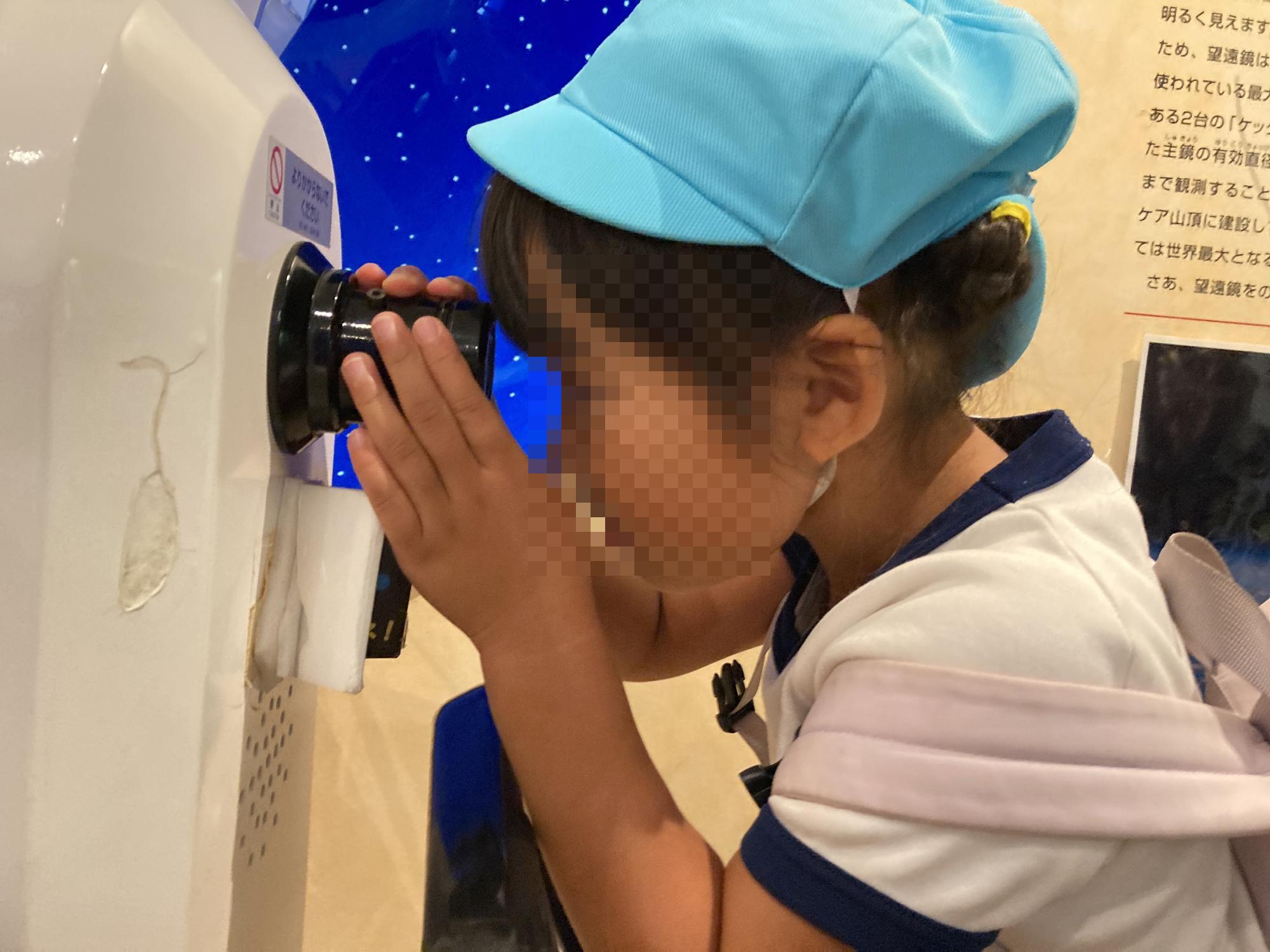 望遠鏡を覗いて星を見る幼児