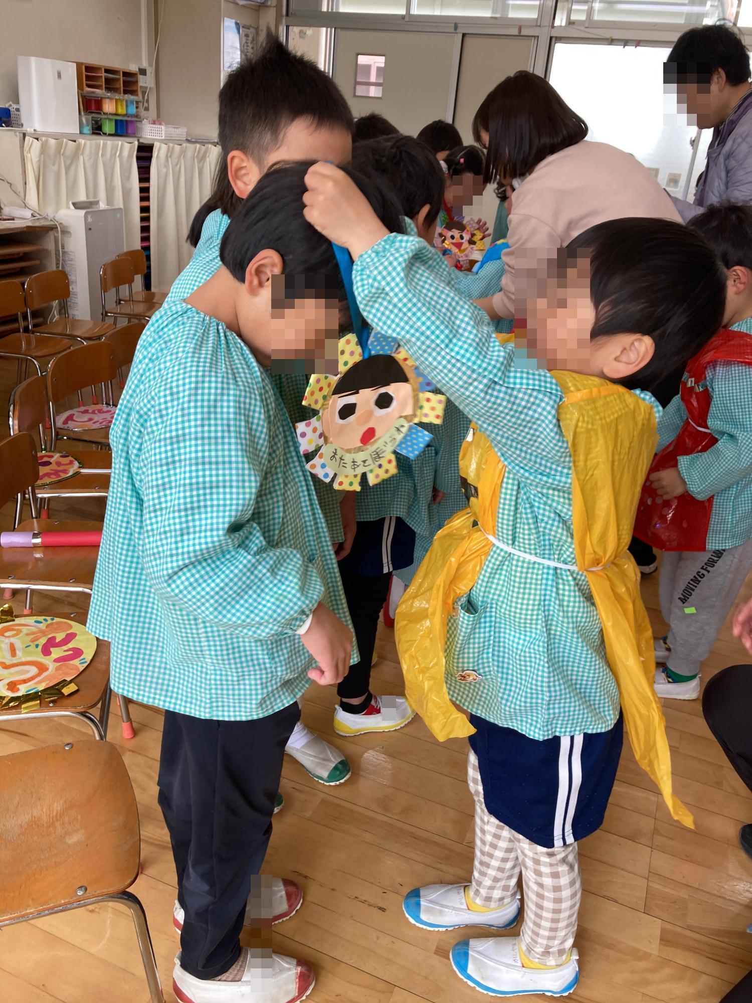 メダルを年長児の首にかける年少児
