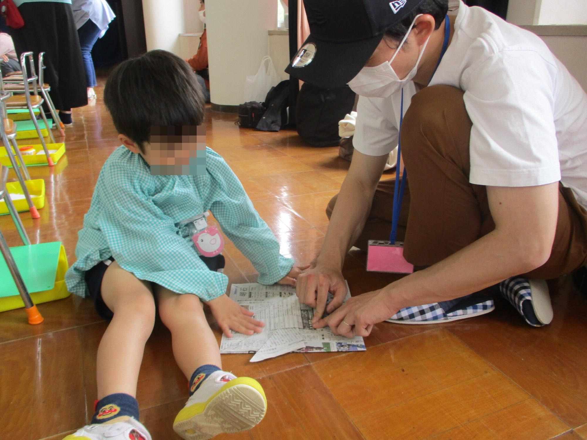 親子で新聞紙カブトを折る5歳児