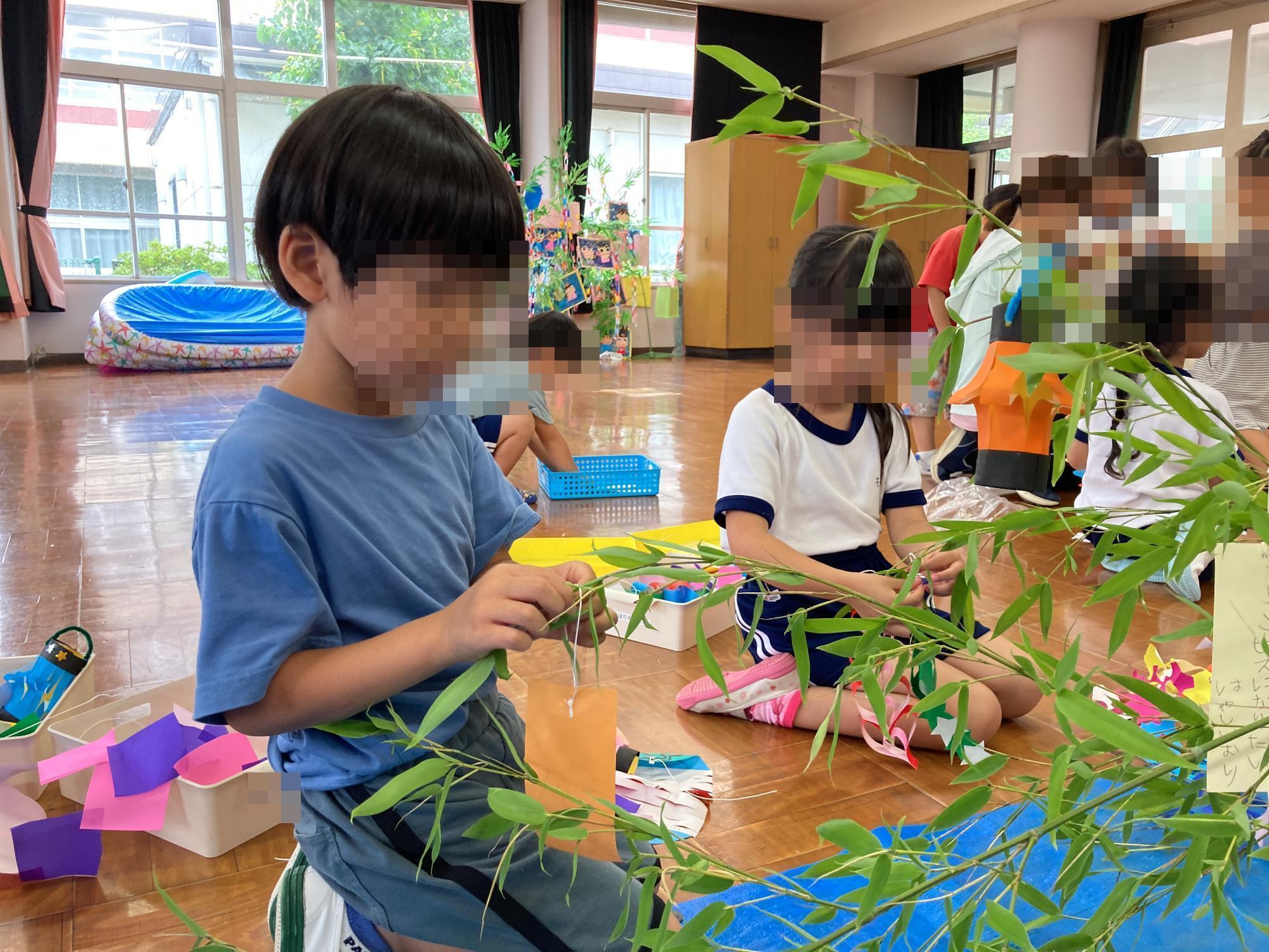 七夕飾りを笹に飾る幼児