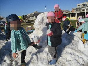 幼児が雪山の上で、雪の穴を掘っている