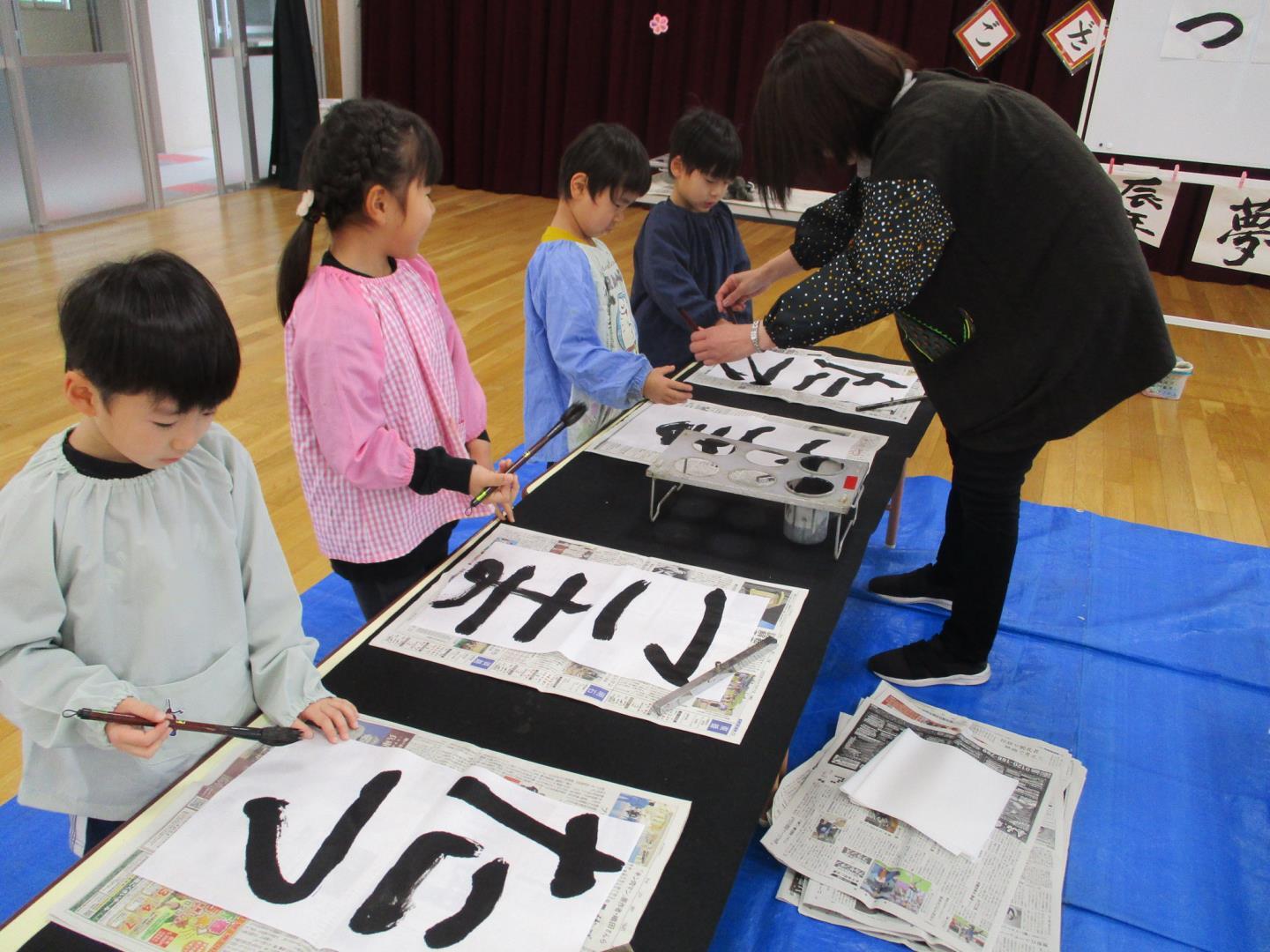 子ども達が園長先生に教えていただきながら、書き初めをしているところ。
