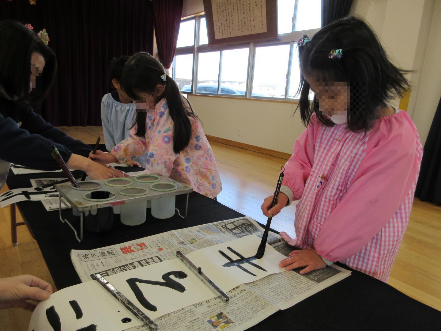 園長先生に教えていただいて書初めをする様子